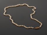 a pearl necklace with a gold clasp on a black surface