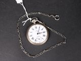 une montre de poche en argent attachée à une chaîne, posée sur une surface noire