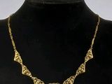 collier plaqué or avec un motif géométrique, présenté autour du cou d'un mannequin