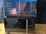 a microwave sitting on top of a table next to a basket