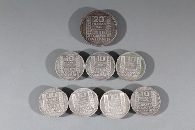 six pièces d'argent sont disposées en pyramide sur une surface grise