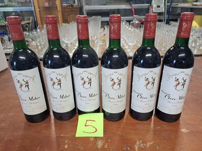 six bouteilles de vin rouge sont alignées sur une table