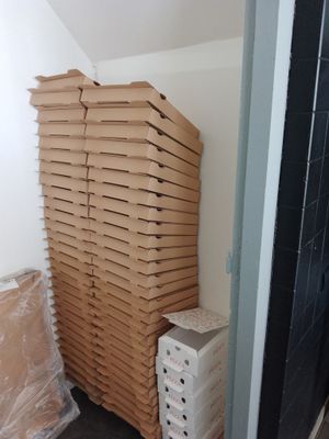 boxes of pizza stacked on top of each other in the corner of a room