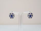 une paire de boucles d'oreilles en saphir et diamants, présentées sur un socle transparent