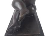 statue of a woman laying on her stomach on top of a black base