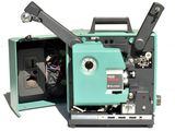 un vieux projecteur de cinéma posé, ouvert, sur une surface blanche