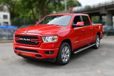 Le camion rouge de la marque Ram est garé sur un parking près d'un pont
