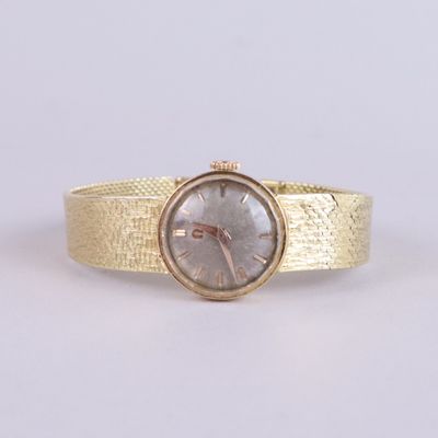 a close up of a gold wrist watch on a white surface