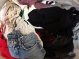 a pile of clothes that is on a bed