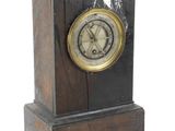 une petite horloge en bois avec un cadran noir sur fond blanc
