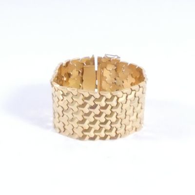 gros plan d'un bracelet en or sur une surface blanche