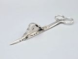 silver scissors on a white surface with a small metal object in the middle