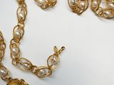 a gold necklace and earring set on a white surface