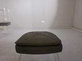 a glass stool with a black seat in a white room