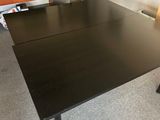 a black desk with a chair and a television in the corner