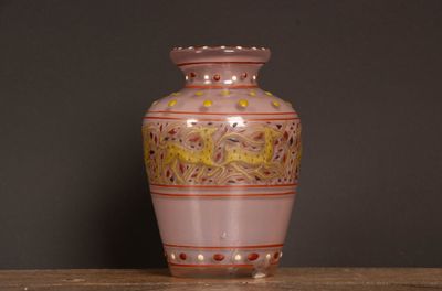 un vase rose posé sur une table en bois, sur fond noir