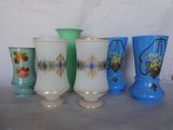 Plusieurs vases sont alignés sur une table devant un fond blanc.