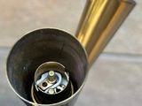 a metal funnel with a brass handle in a bathroom