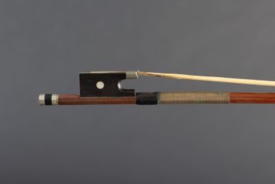 a violin bow and bow rest on a gray background