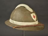 an old helmet with a red cross on it sitting on a stand