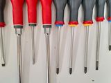 seven different types of screwdrivers lined up on a white surface