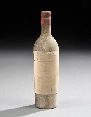 une vieille bouteille de vin posée sur une table blanche
