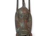 une image représentant un masque en bronze accroché à un mur