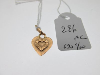 un gros plan sur un pendentif en forme de cœur en or, sur lequel est accrochée une étiquette de prix