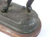 a bronze statue of a man riding a horse on a wooden base