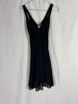 une robe noire suspendue à un cintre sur un drap blanc