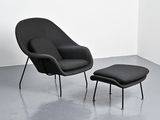 a black chair and ottoman in a room with a white wall