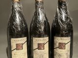 three bottles of wine wrapped in plastic sitting on a table