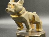 figurine en laiton représentant un chien, posée sur un socle, sur une surface grise