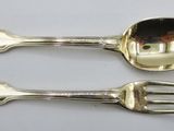 two silver spoons and a fork on a table