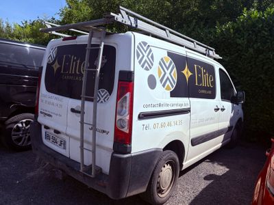 une camionnette blanche garée sur un parking avec des arbres en arrière-plan