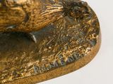 bronze statue of a bird on a rock on a white surface