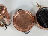 three old copper pots and pans sitting on a white surface