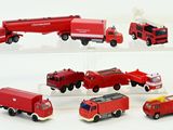 several toy fire trucks are lined up on a white surface