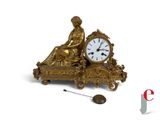 a gold clock sitting on top of a table next to a clock