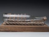 a ship in a glass bottle on a wooden base