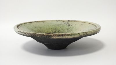 un bol vert bordé de noir sur un fond blanc