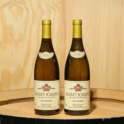 two bottles of wine sitting on top of a barrel