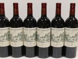 six bottles of red wine are lined up on a table