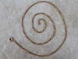 a close up of a gold chain on a white surface