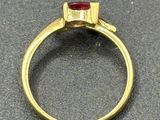 a close up of a gold ring with a red stone in it
