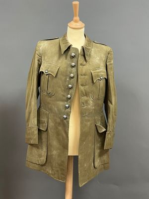 une vieille veste militaire posée sur un mannequin, sur fond gris