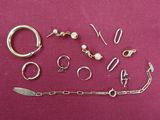 many different types of silver jewelry on a pink surface