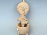 une image représentant une figurine en argile représentant une personne assise dans un pot