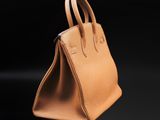 a tan leather handbag on a black background
