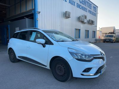 Une voiture blanche est garée devant un immeuble.